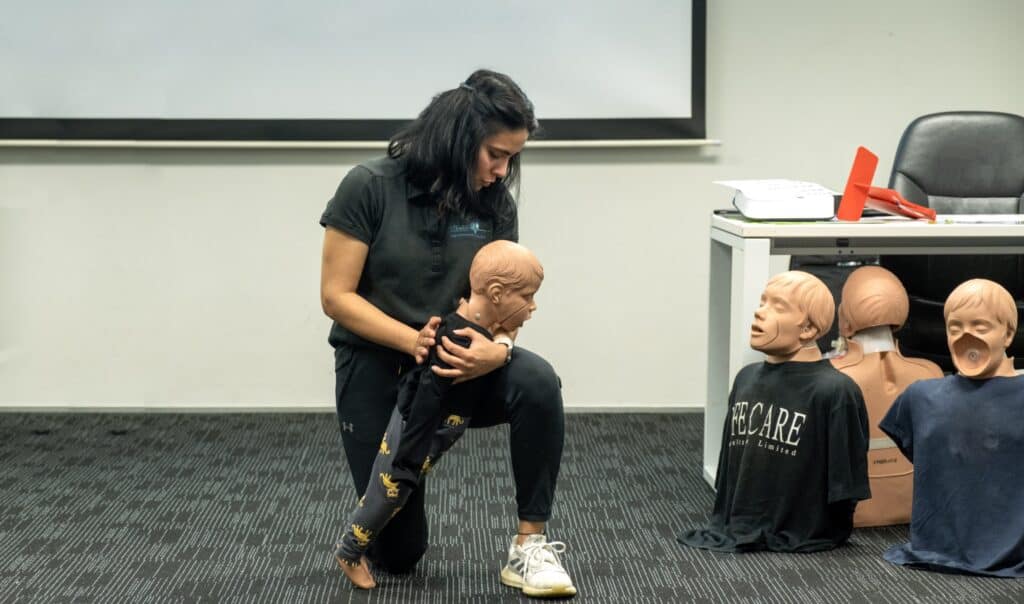 Instructor demonstrating infant CPR techniques with a mannequin during Life Care training.