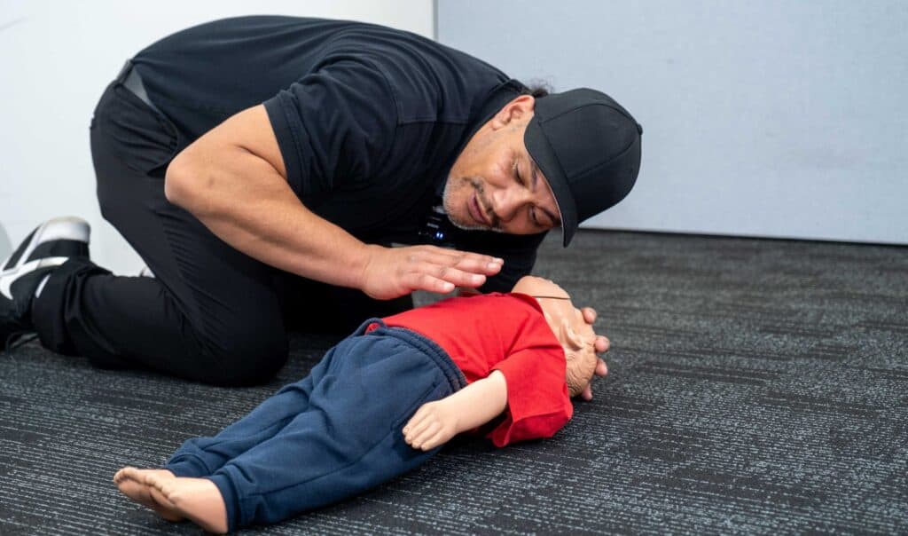 Instructor practicing CPR on an infant dummy during a Life Care training session.